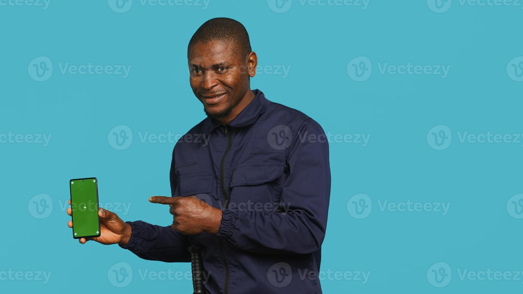 Portrait of happy security guard at work showcasing green screen laptop while overseeing premises. Cheerful private law enforcement worker presenting chroma key notebook, studio backdrop, camera A photo