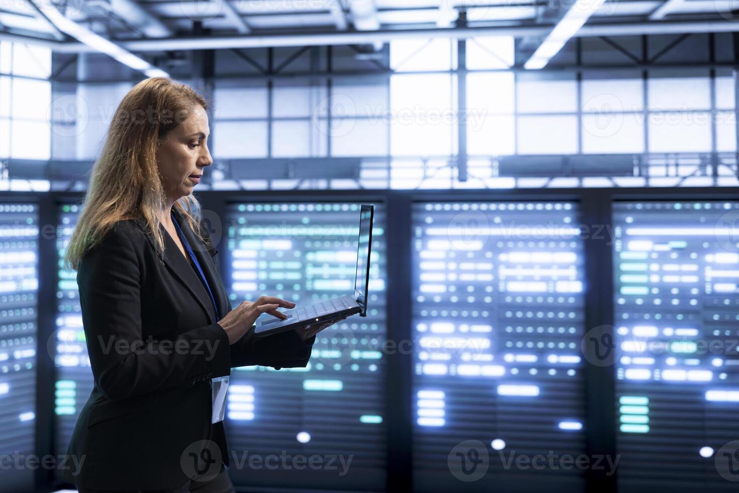 Software developer in data center implementing backup solutions to protect against data loss using laptop, ensuring efficient recovery processes. Woman in server room resolving technical issues photo