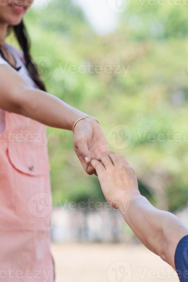 A young man is holding the hand of a young woman who is his lover to express his love and promise to love and care for each other forever. The concept of friendship, love and kindness photo