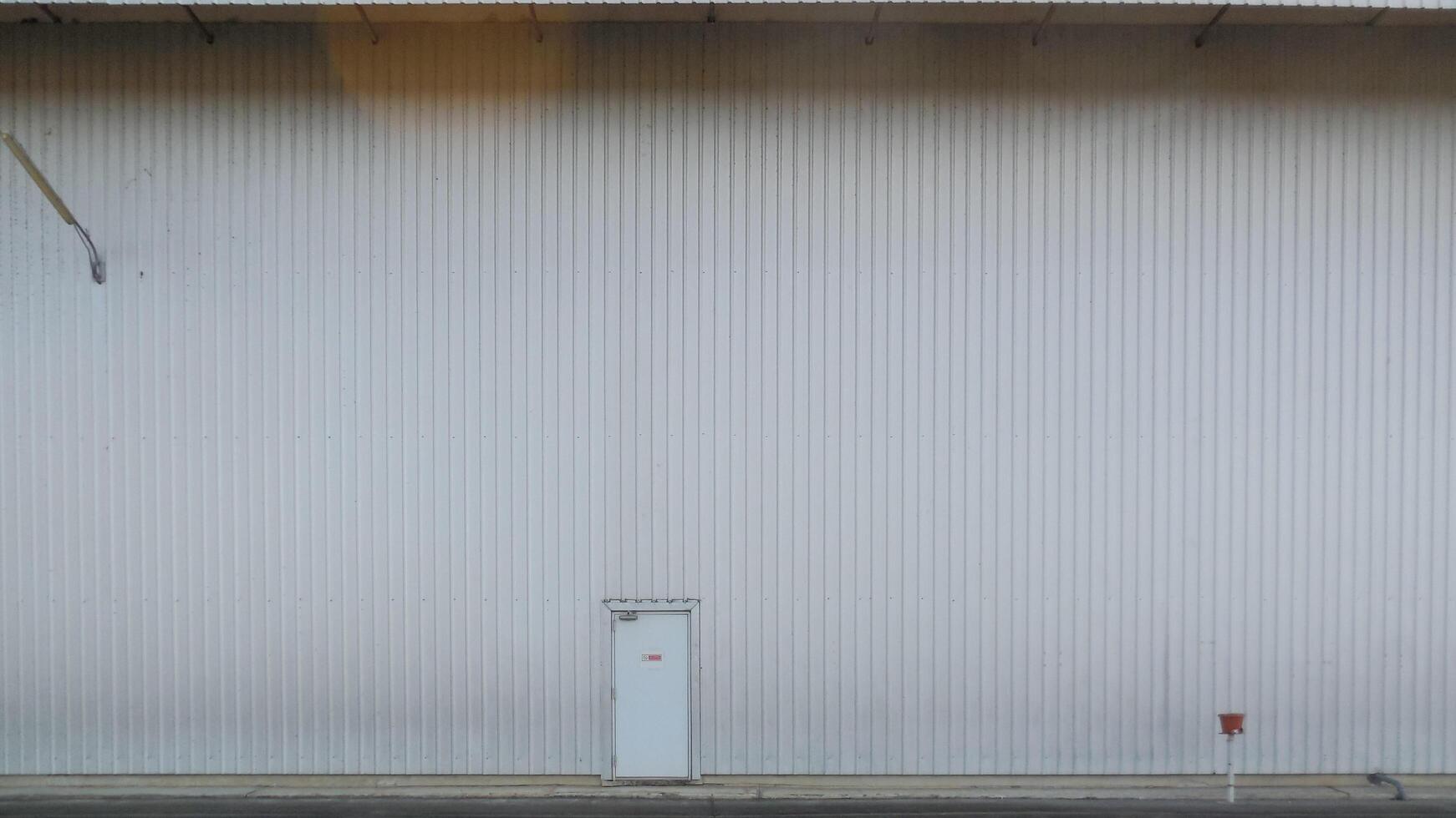 outer wall of a large warehouse with access doors for caregivers. The metal wall background of the spacious storage warehouse and caretaker entrance on the wall also provides space for messages. photo