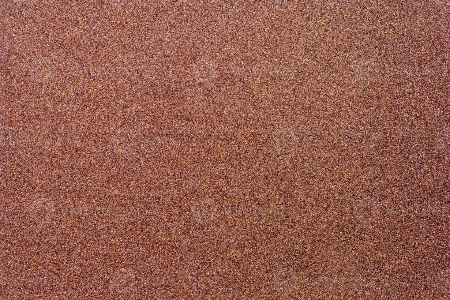 Blurred background of brown sandpaper for inserting text. Sandpaper backgrounds are made from natural materials for polishing wood and steel to a smooth surface before painting. photo