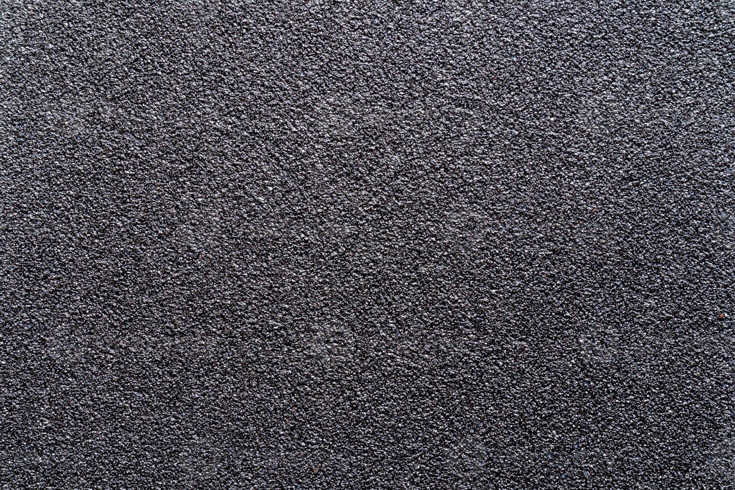 Sandpaper texture background gives a beautiful pattern of black sand grains on sandpaper, suitable as a background for inserting text. Copy Space for designers to use on sandpaper. photo
