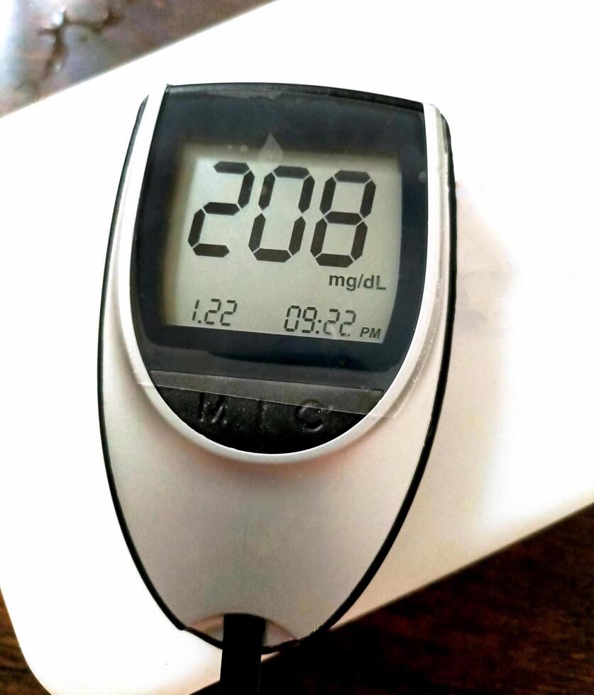 A close up of blood glucose meter with high sugar reading on wooden table photo
