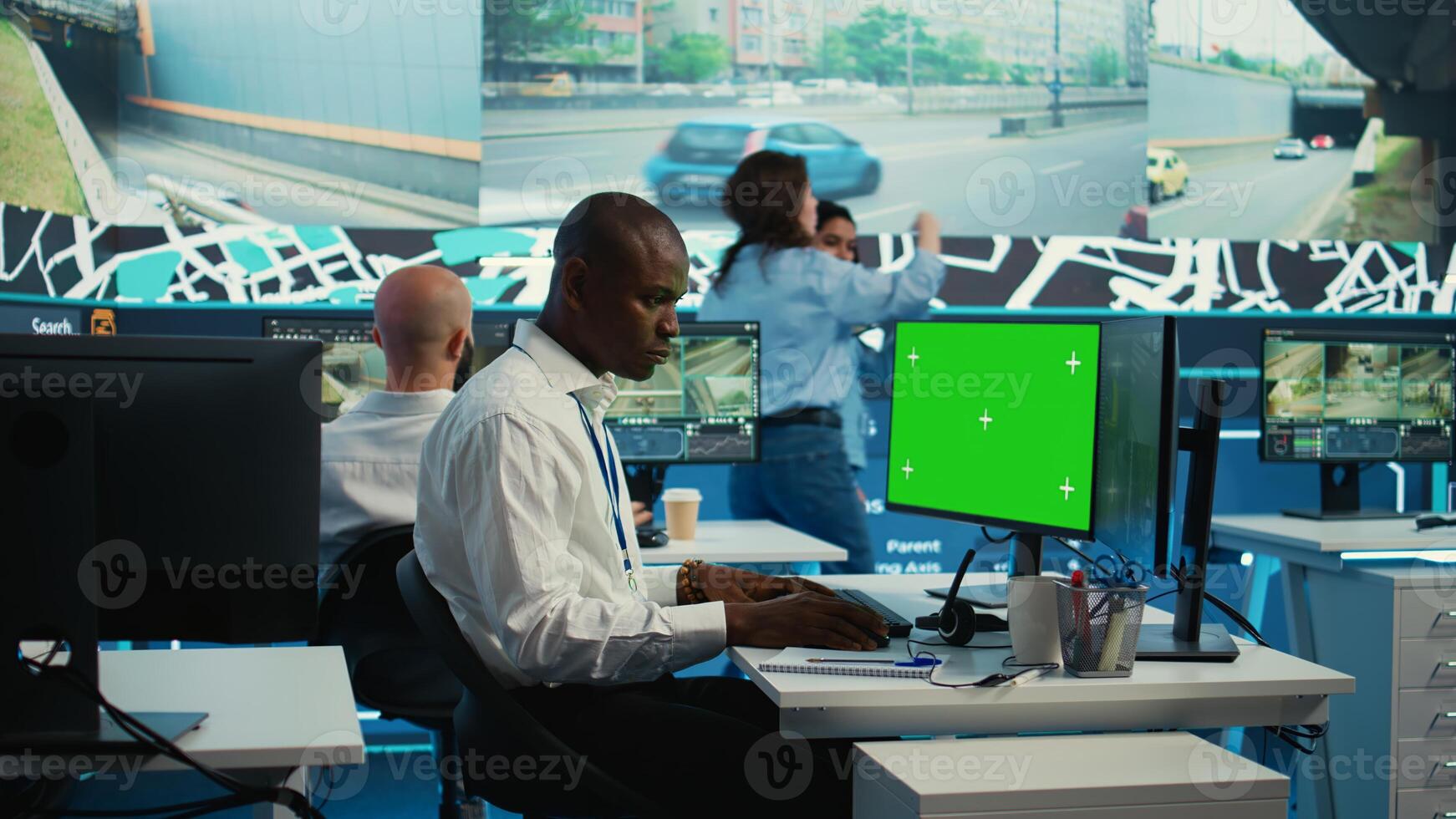African american employee using greenscreen display and CCTV real time footage, communicating gps coordinates for order shipment and delivery. Control center operator uses surveillance. Camera B. photo