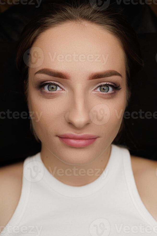 Cute girl model poses after permanent eyebrow makeup procedure result after eyebrow procedure. Permanent eyebrow makeup PMU for brunettes photo