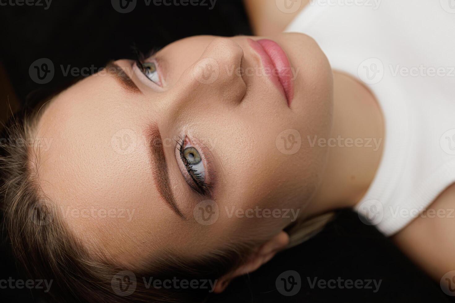 Beautiful brunette poses after permanent eyebrow makeup procedure, permanent makeup result after. Permanent eyebrow makeup PMU for brunettes photo