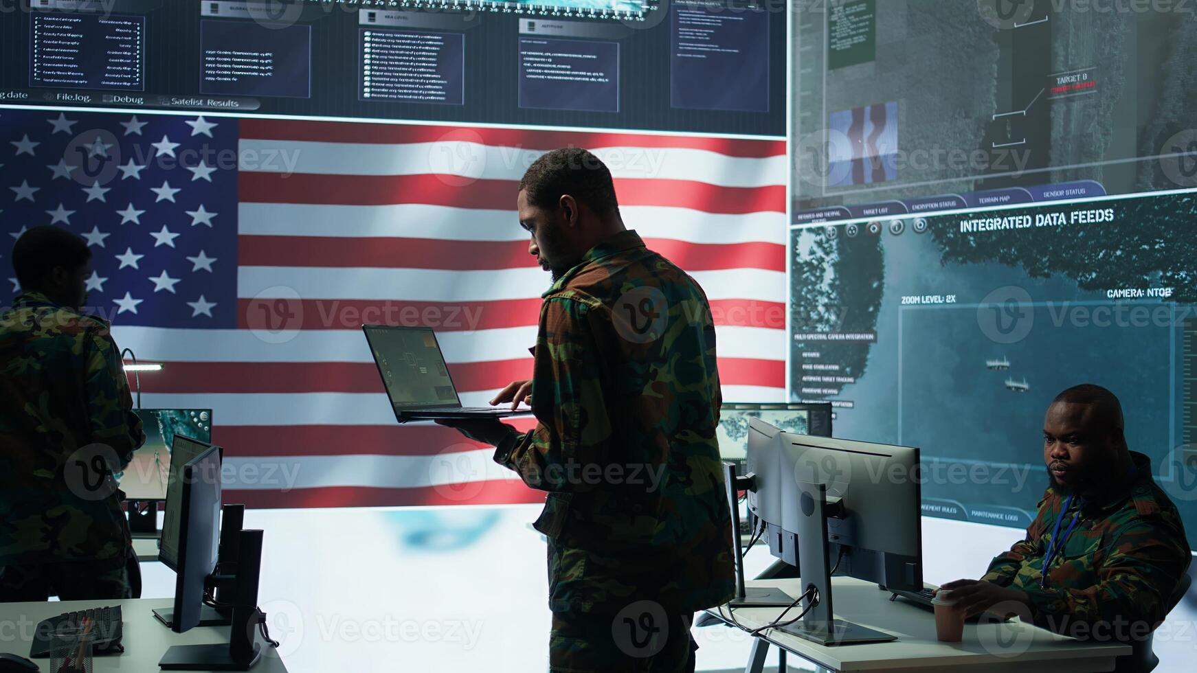 Professionals in US military uniforms operate computers and big screen, working on surveillance and intelligence to ensure national security from a high tech control center. Camera B. photo