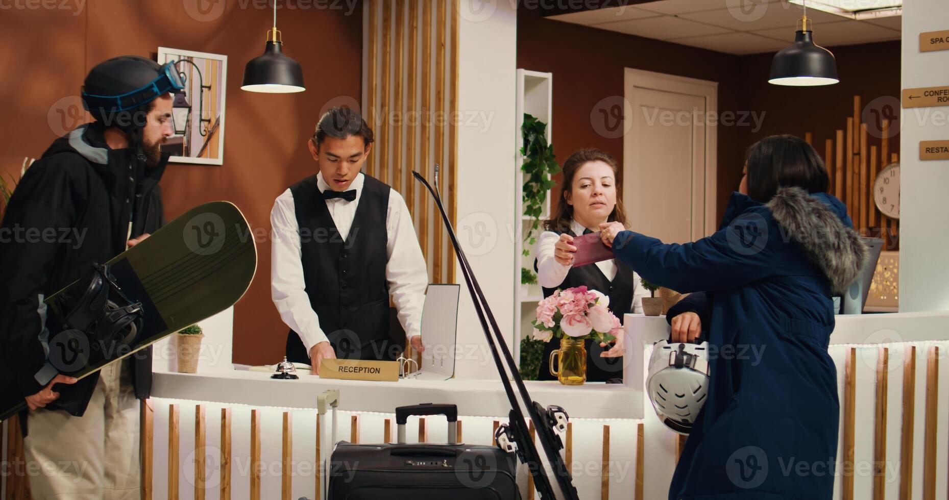 Staff checking tourists passport id at reception, doing check in procedure before leaving on alpine slope with skiing gear. Hotel guests eager to have fun with winter activities. photo