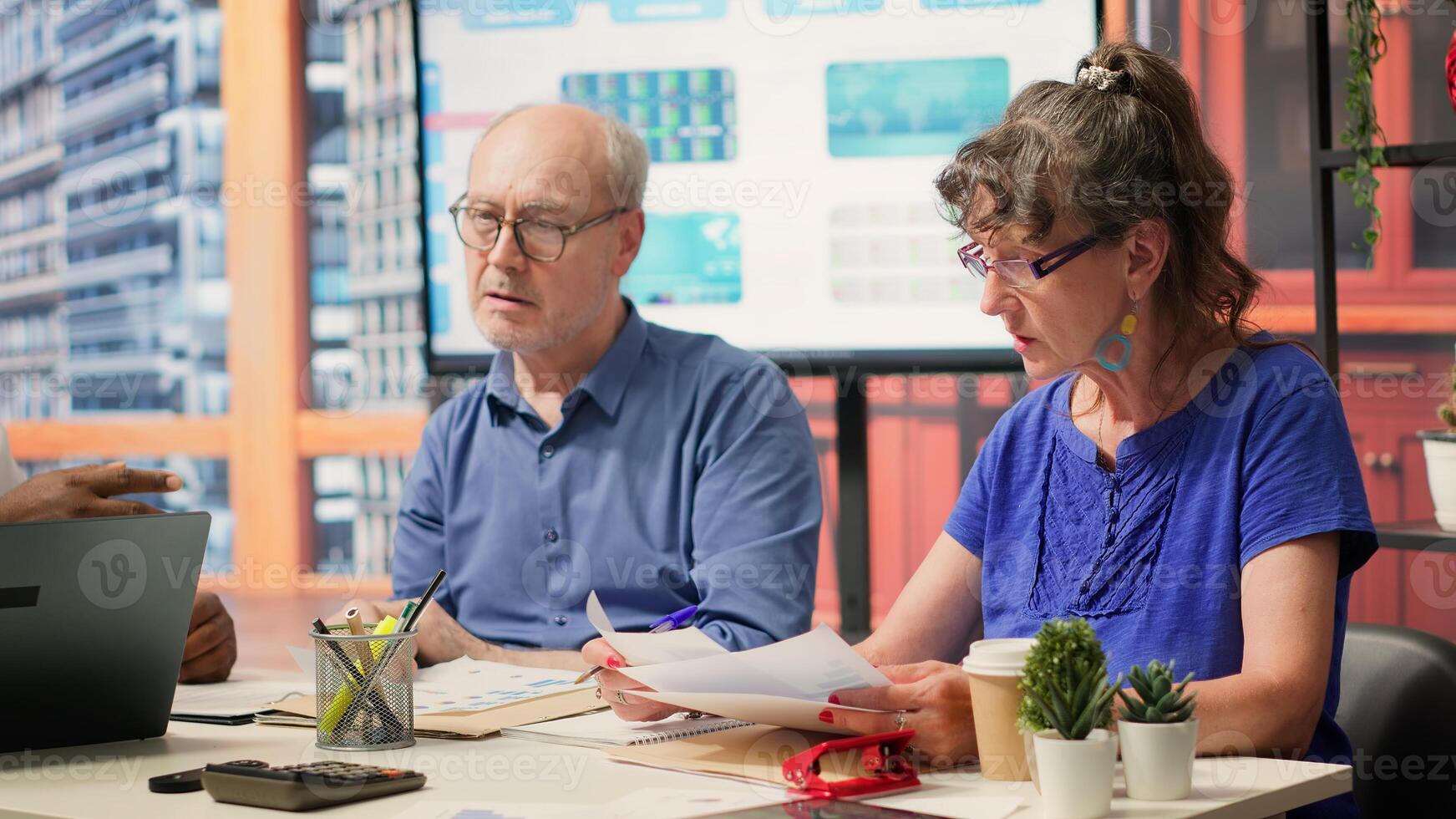 Financial advisor reading the retirement plan contract at the end of the agreement between senior people and the insurance agency. Agent helping couple to secure their pension. Camera A. photo