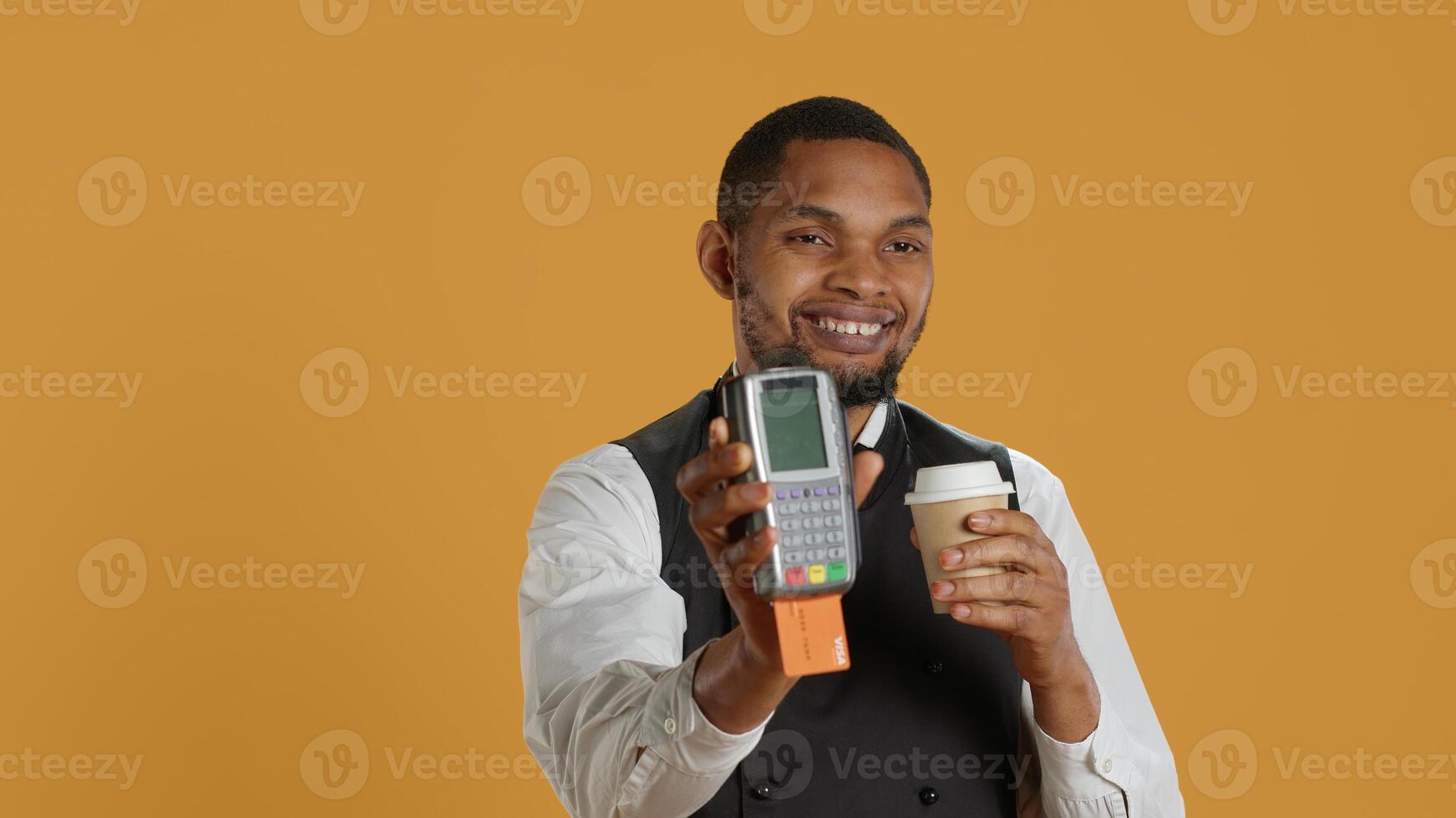 Professional friendly waiter showing the pos terminal with a credit card, symbolizing electronic payments for a meal. Restaurant employee works in a service oriented industry. Camera A. photo