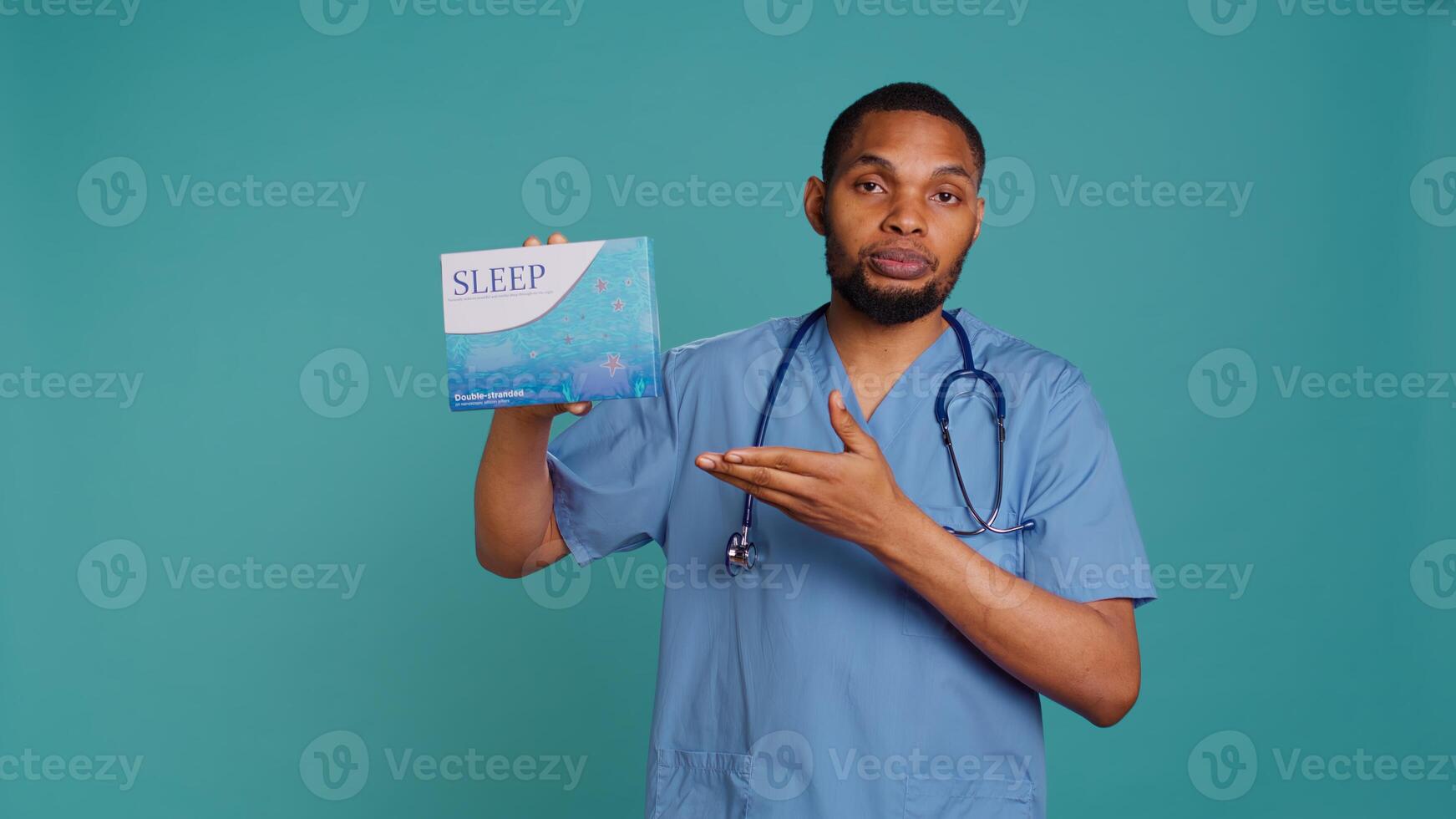 Portrait of african american medic holding sleep deprivation medicine package for insomniacs, studio background. Healthcare specialist recommending tablets for patients with insomnia, camera B photo