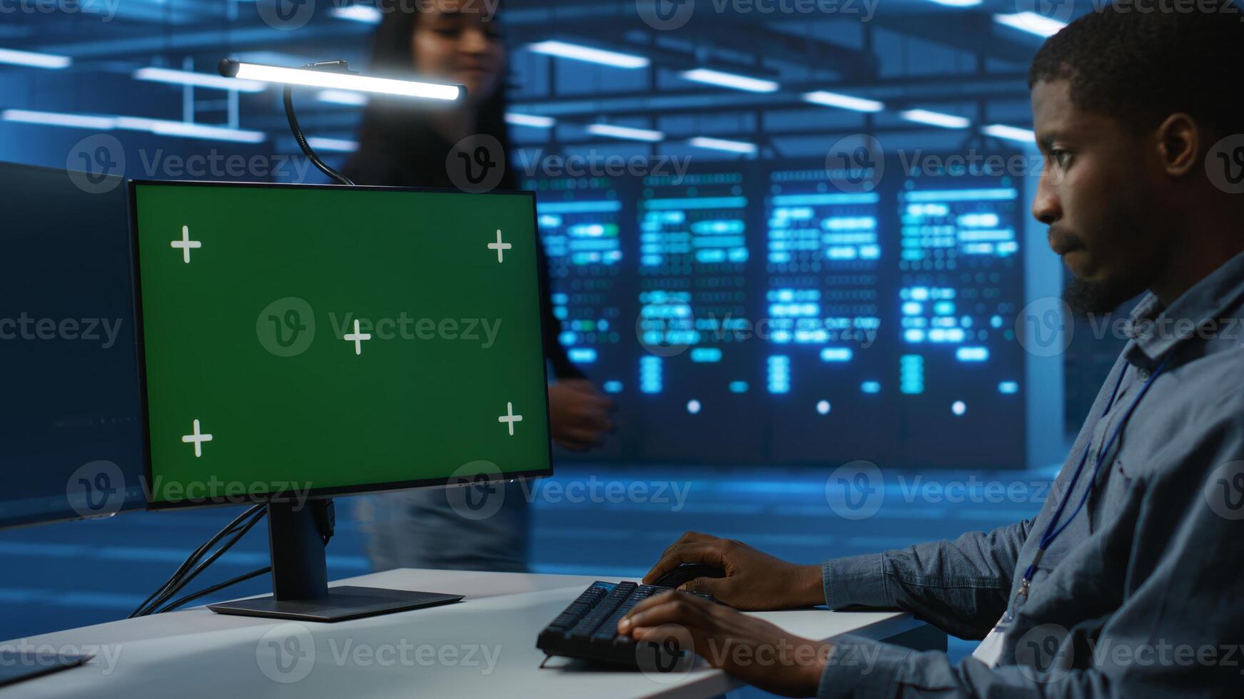 African american software developer coding on green screen computer, upgrading equipment. System administrator at PC desk overseeing server clusters using chroma key monitor photo