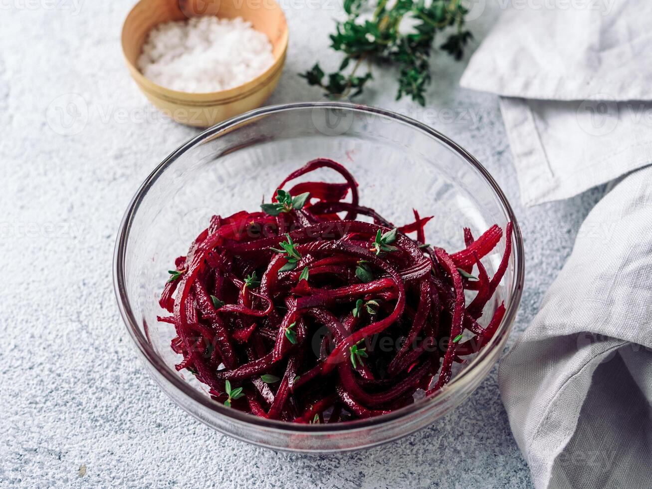 Raw beetroot noodles salad. Vegetable noodles - beet spaghetti in glass plate over gray cement background. Copy space for text. Ideas and recipe for Clean eating, raw vegetarian food concept. photo