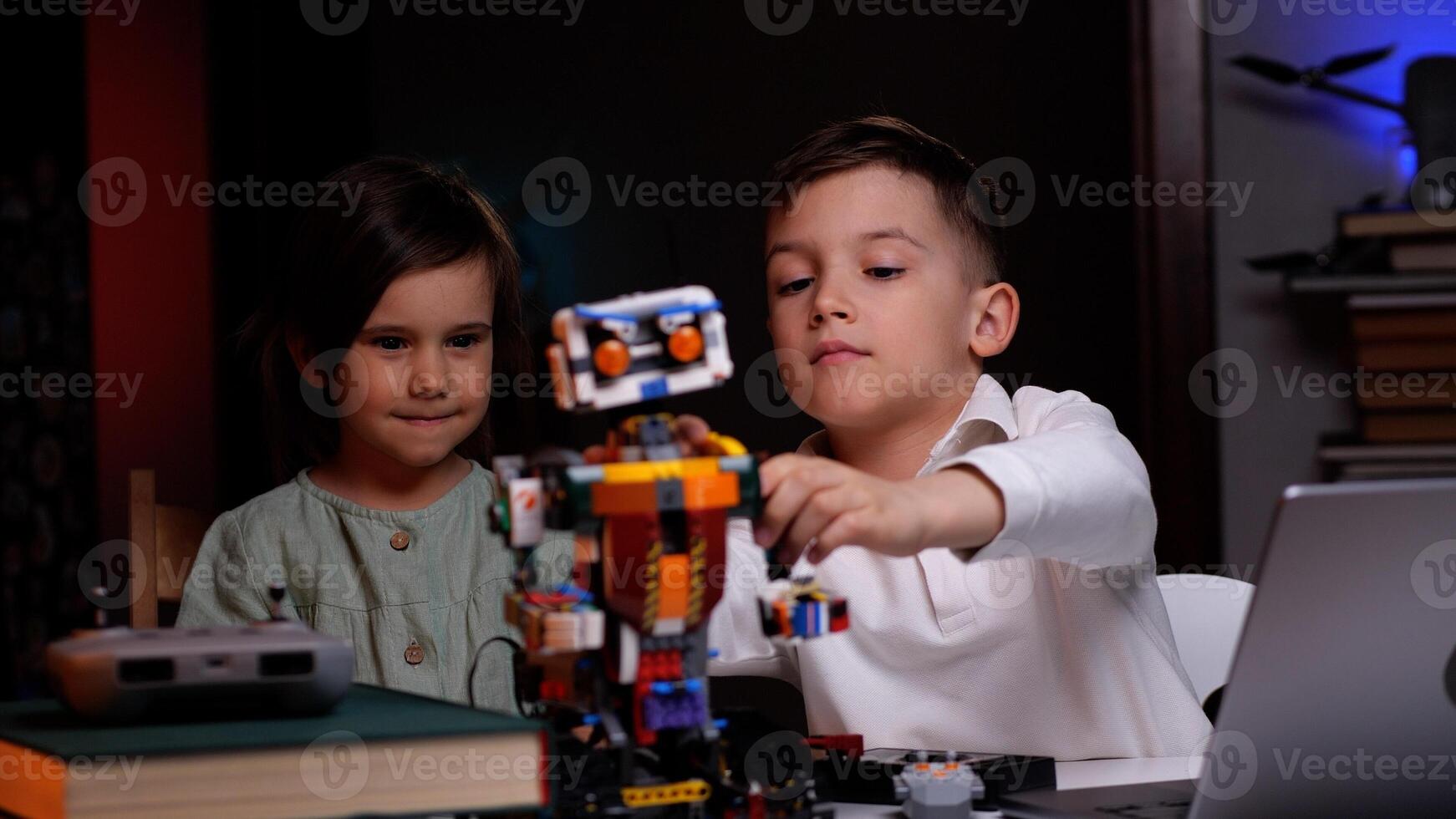 Two kids playing with robot from building blocks at home photo