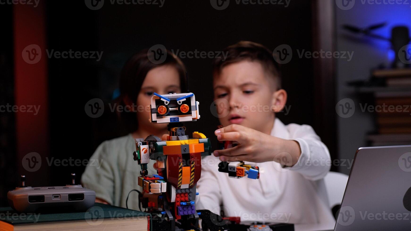 Two kids programming robot from building blocks at home photo