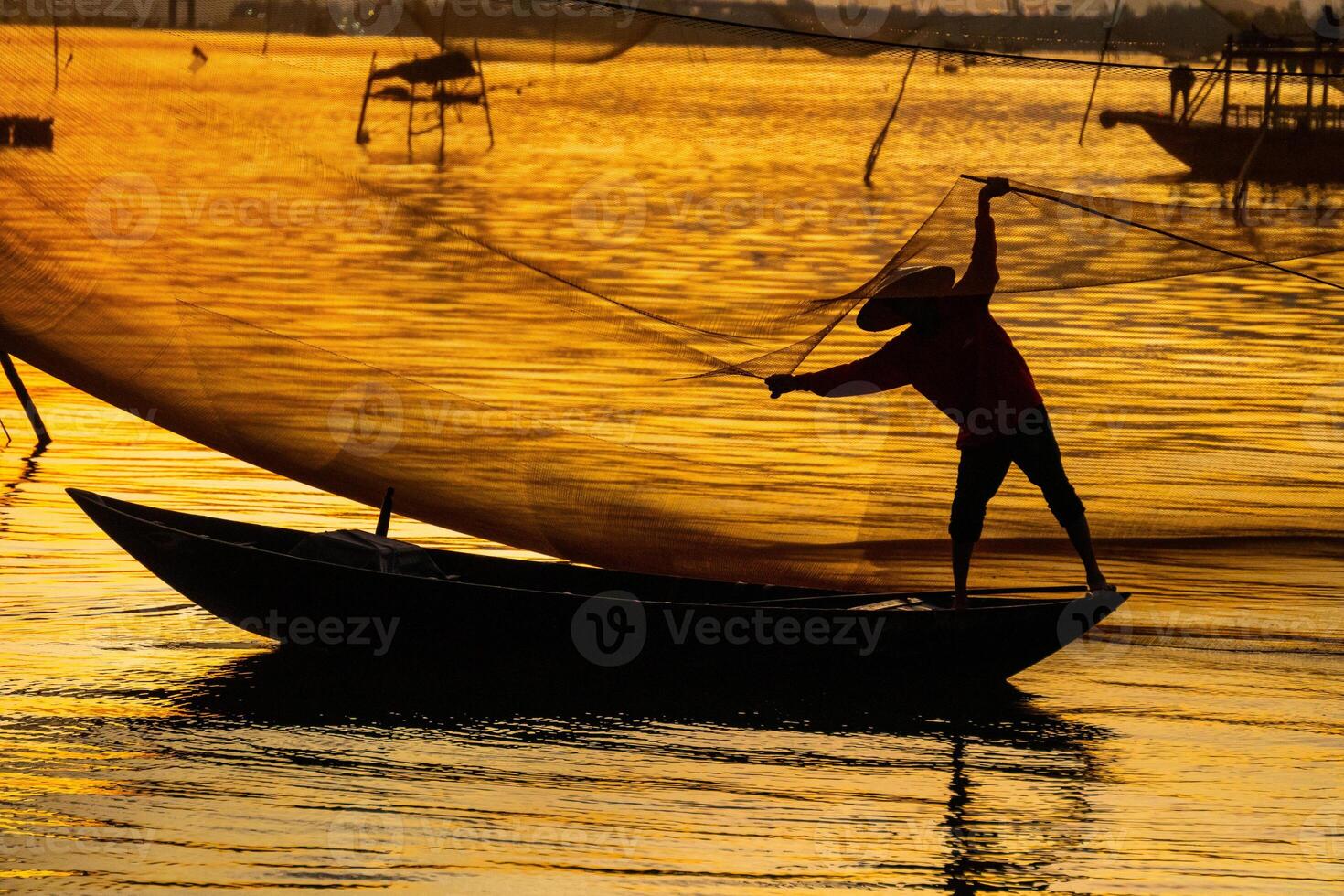 View of unidentified fisherman checks his nets in early morning on river in Hoi An ancient town, Quang Nam Province, Vietnam photo