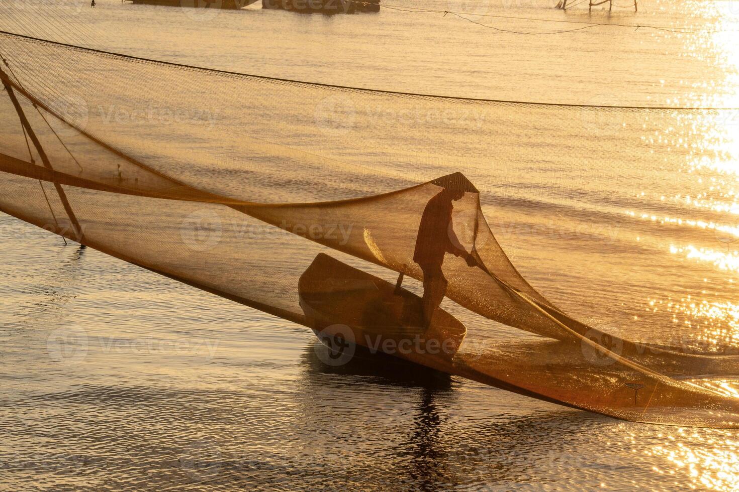View of unidentified fisherman checks his nets in early morning on river in Hoi An ancient town, Quang Nam Province, Vietnam photo