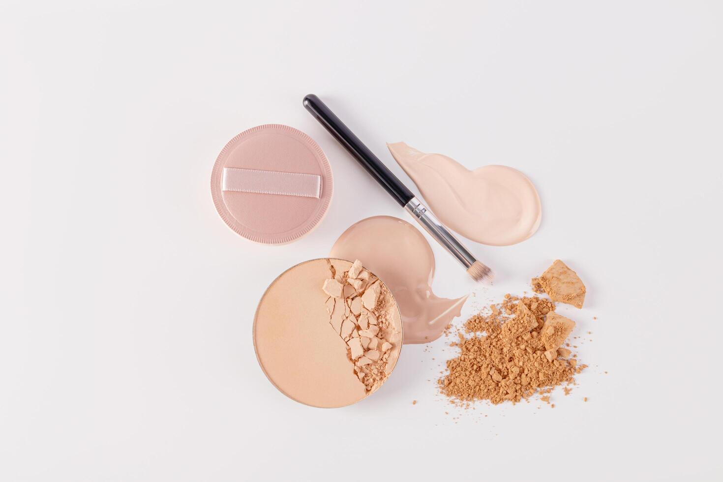 two samples of Liquid different tones , loose powder, block of compact powder with a chic makeup brush. top view. white background. close up photo