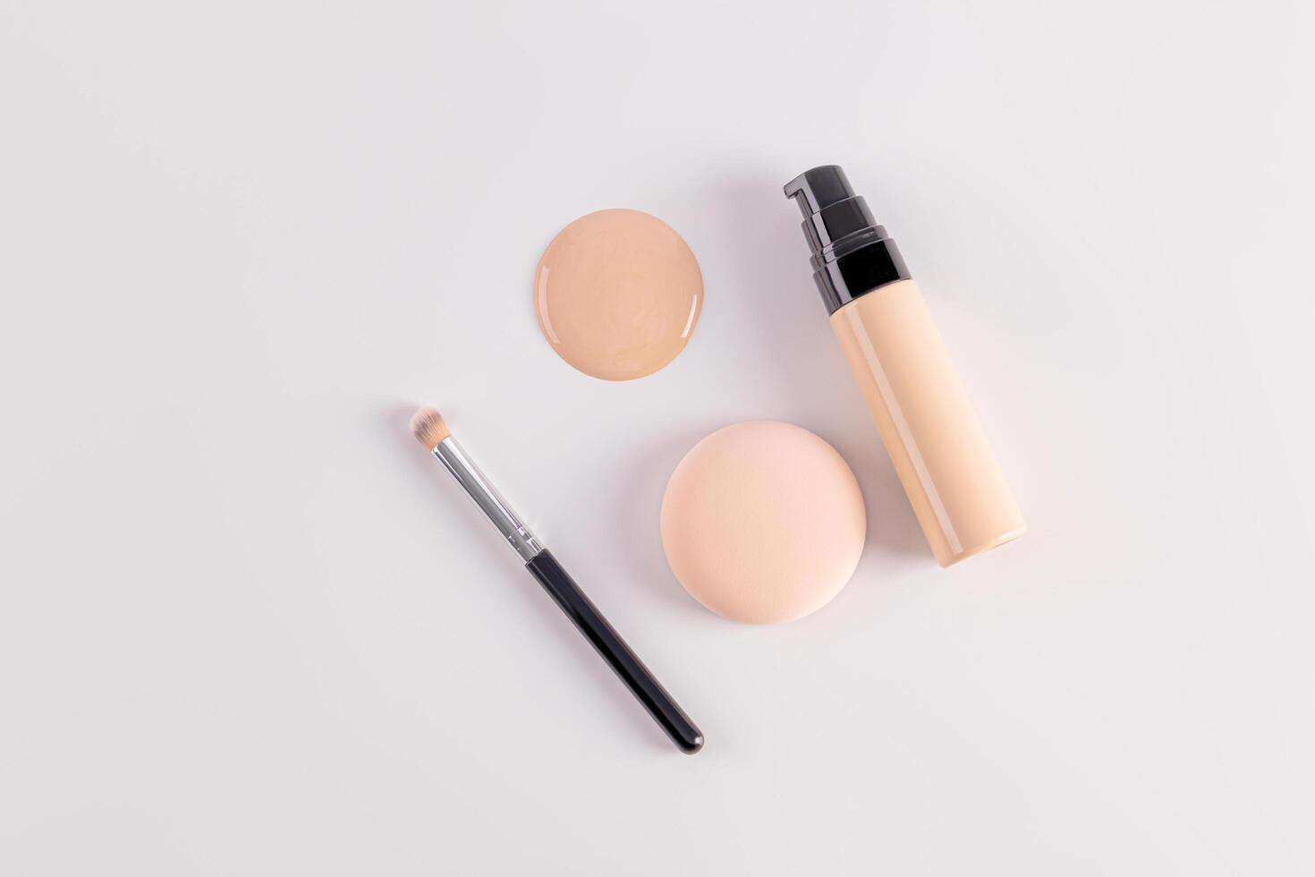 Bottle with dispenser with foundation powder, round sponge, brush for applying makeup, round sample of powder. top view. cosmetic background. photo