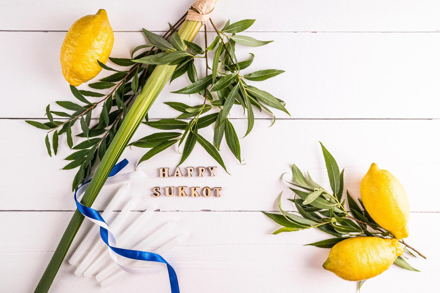 A festive background for the Jewish festival of Sukkot with traditional symbols and candles. white wooden background. Wooden letters of the Sukkot. photo