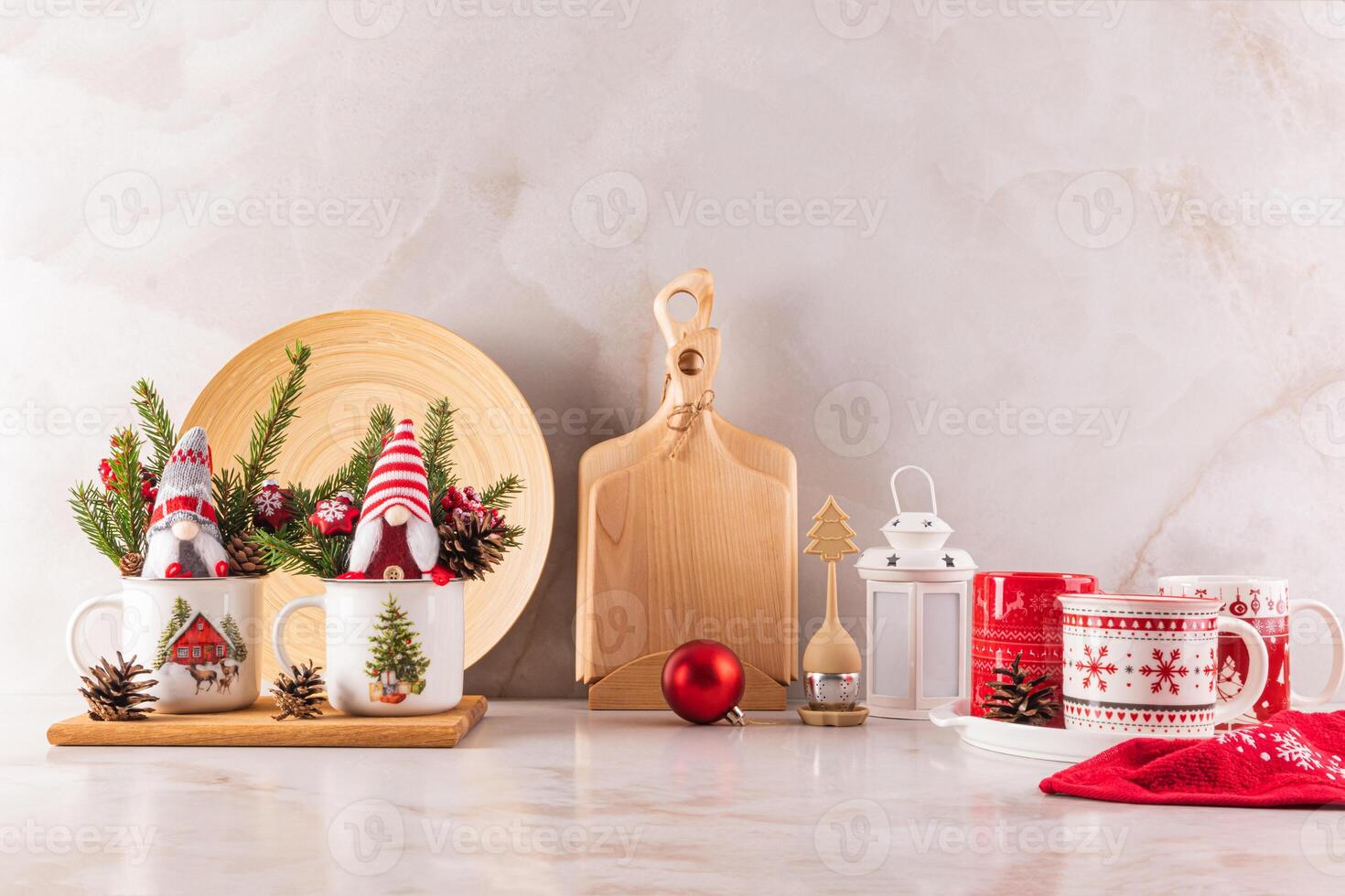 Two New Year's gnomes in mugs and spruce branches on the kitchen countertop with wooden eco utensils. Christmas mood in the kitchen space. photo