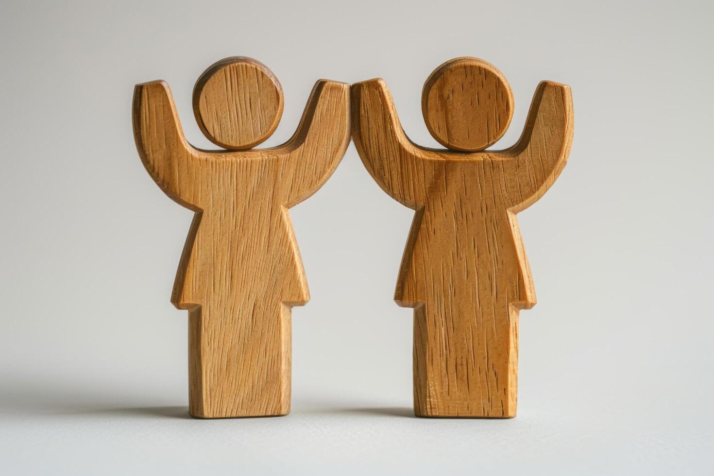 Wooden Figures of People with Raised Arms on Neutral Background photo