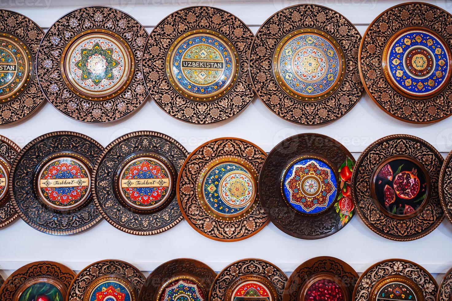 traditional Uzbek wooden handmade gift plates with wood carvings hand-painted in souvenir store of Uzbekistan photo