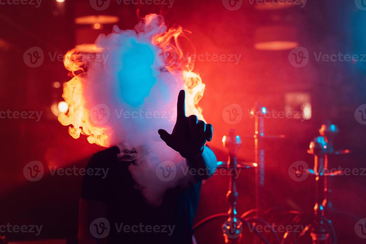 man smokes a hookah and lets out a cloud of smoke photo