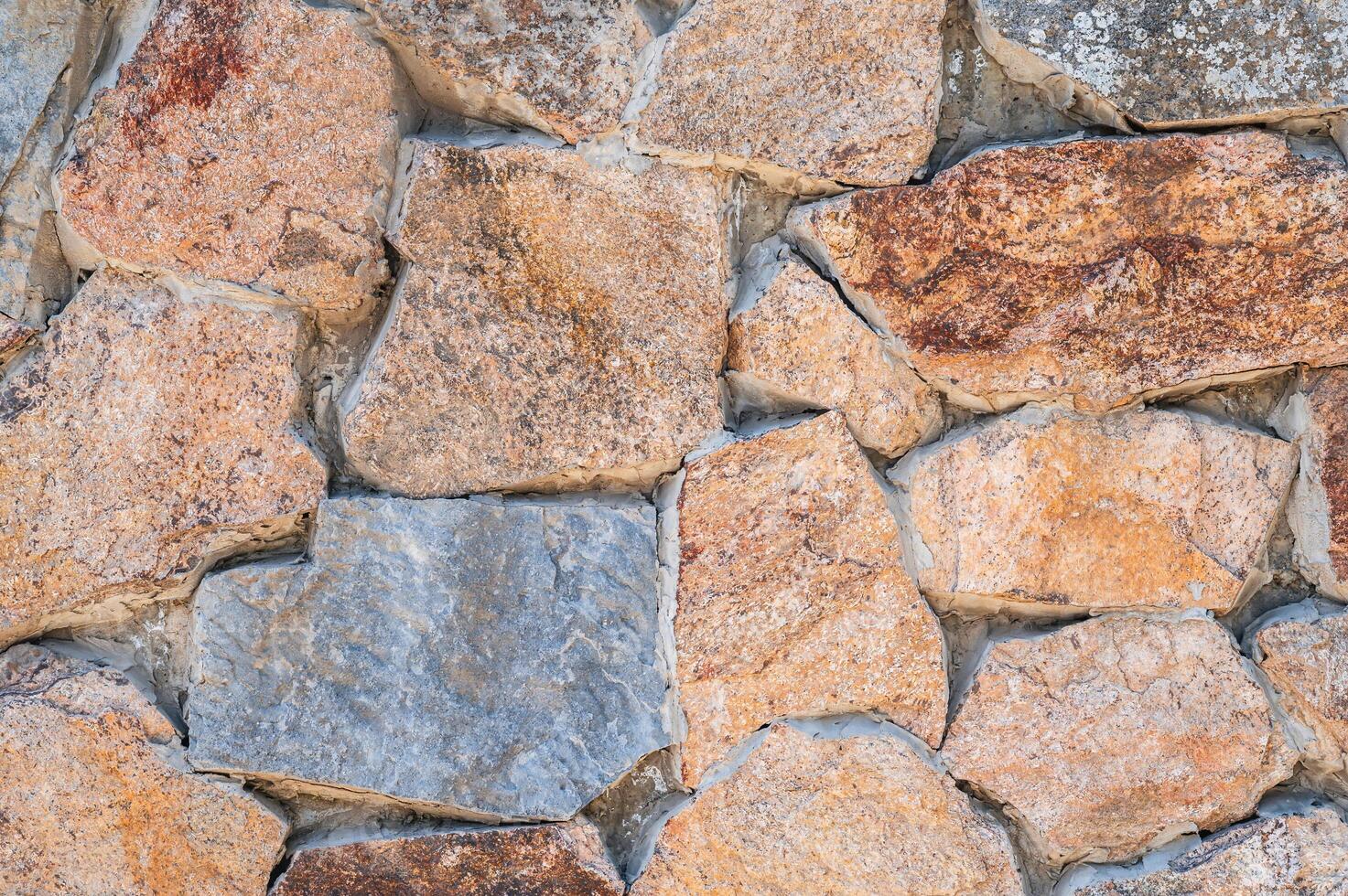 texture of masonry of modern stone wall made of multicolored stones in close up photo