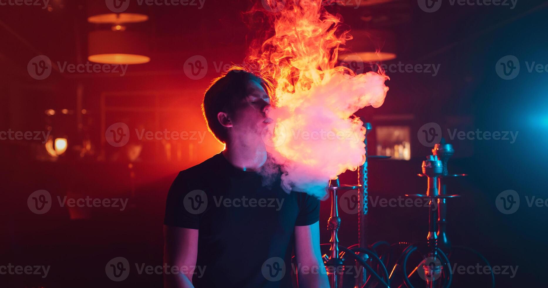 man is relaxing and Smoking a hookah and blowing a cloud of smoke in a lounge cafe photo