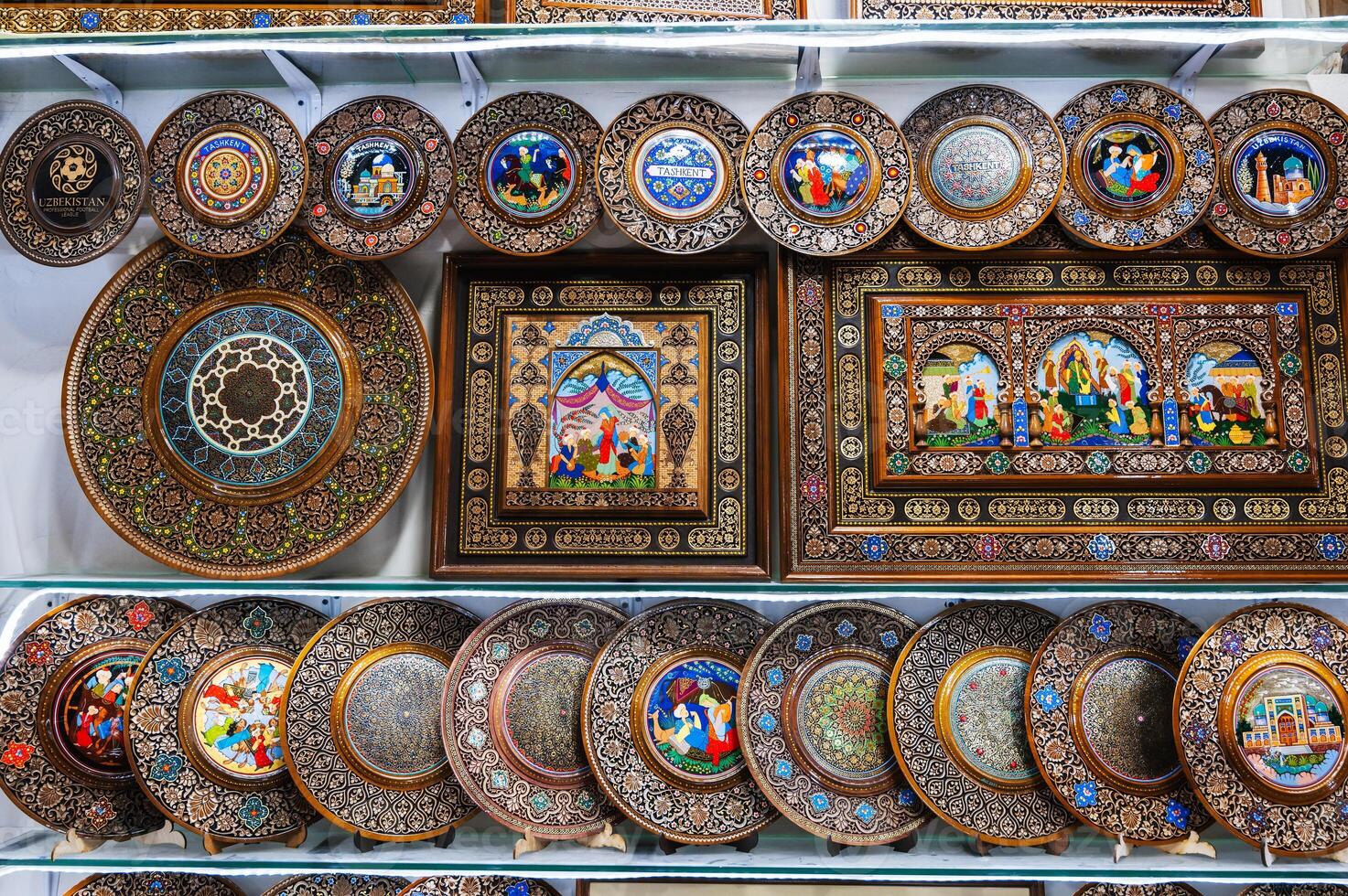 Uzbek wooden gift plates and paintings with wood carvings hand-painted traditional patterns in souvenir shop in Uzbekistan photo