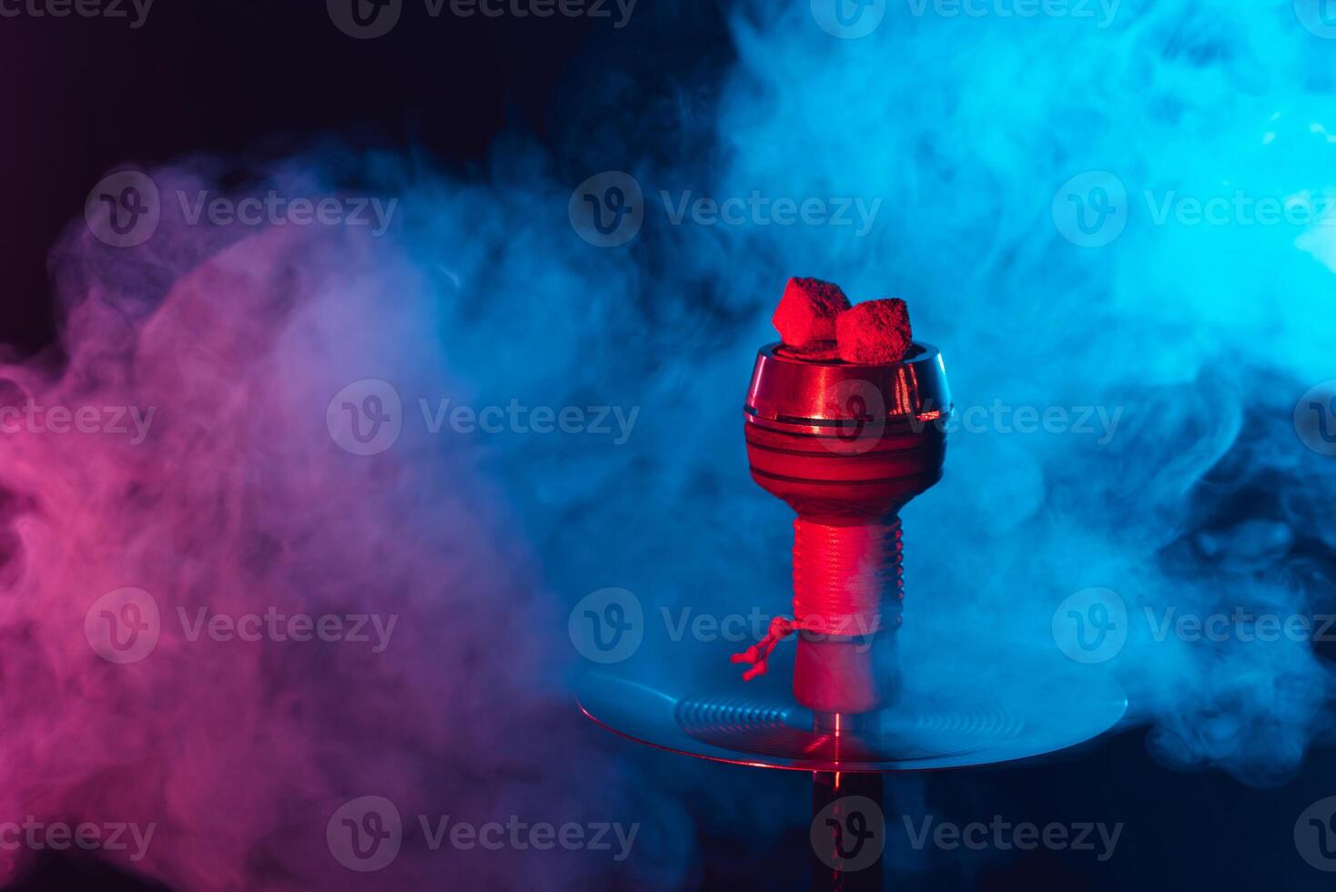 red hot shisha coals in a metal hookah bowl against a background of multicolored smoke photo