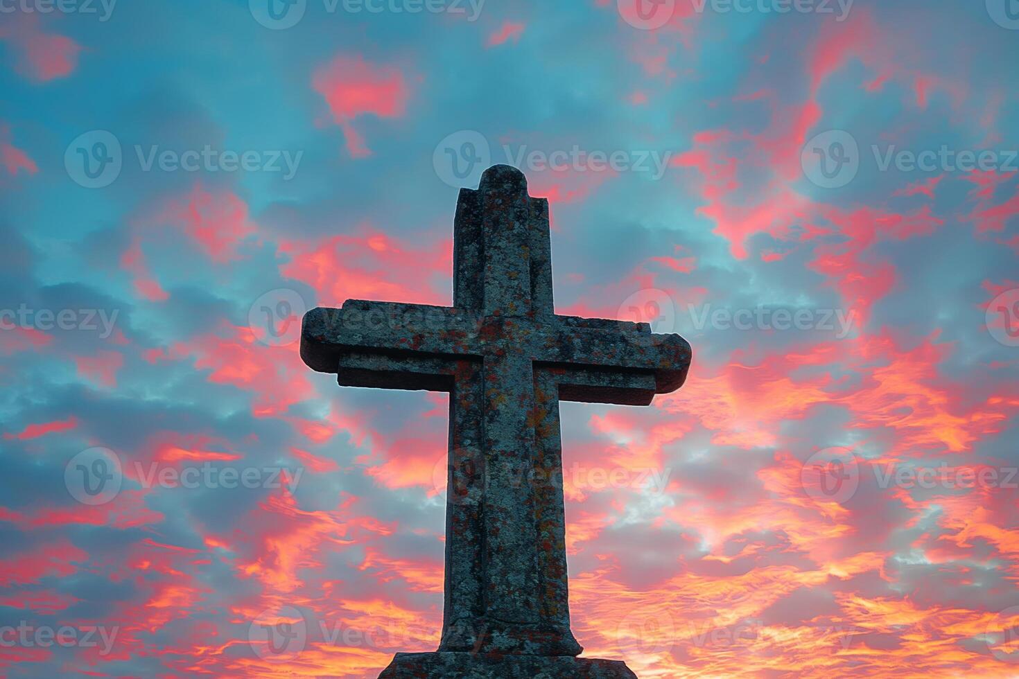 Silhouette of Weathered Cross Against Vibrant Sunrise Sky with Dramatic Clouds photo