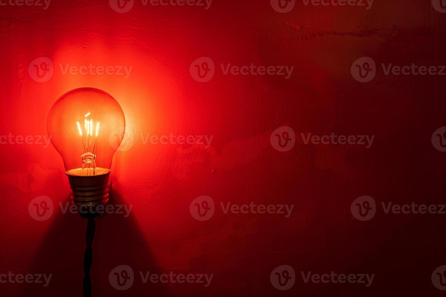 Illuminated Light Bulb Against Red Wall Backdrop in Minimalist Style photo