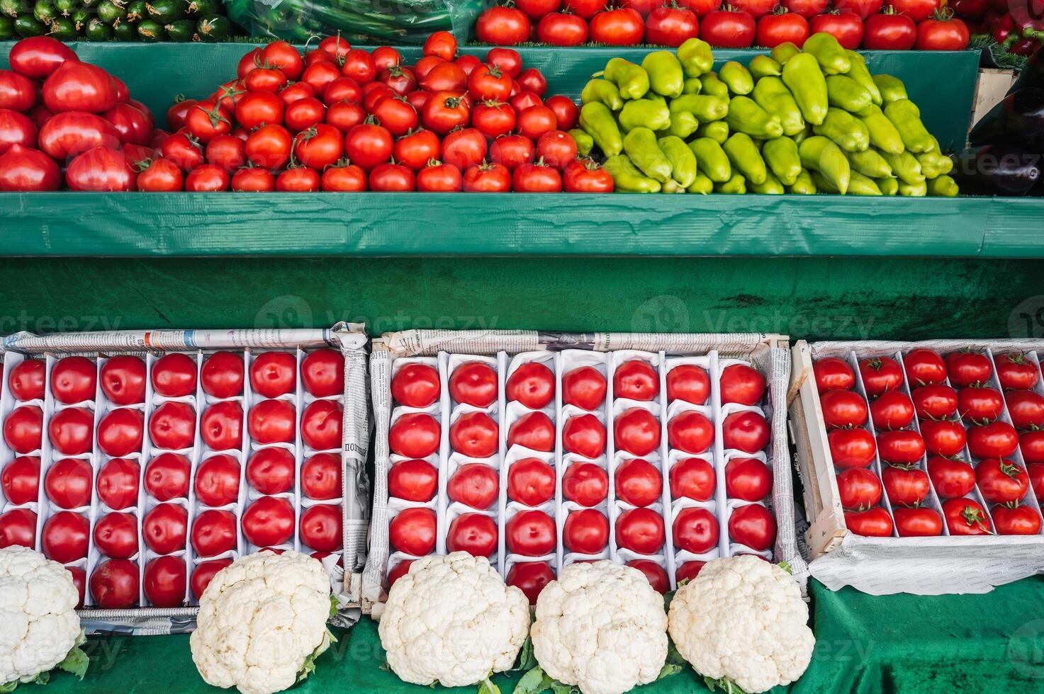 counter with fresh vegetables at grocery farmers market. Tomatoes, cucumbers, cauliflower and peppers on store shelves photo