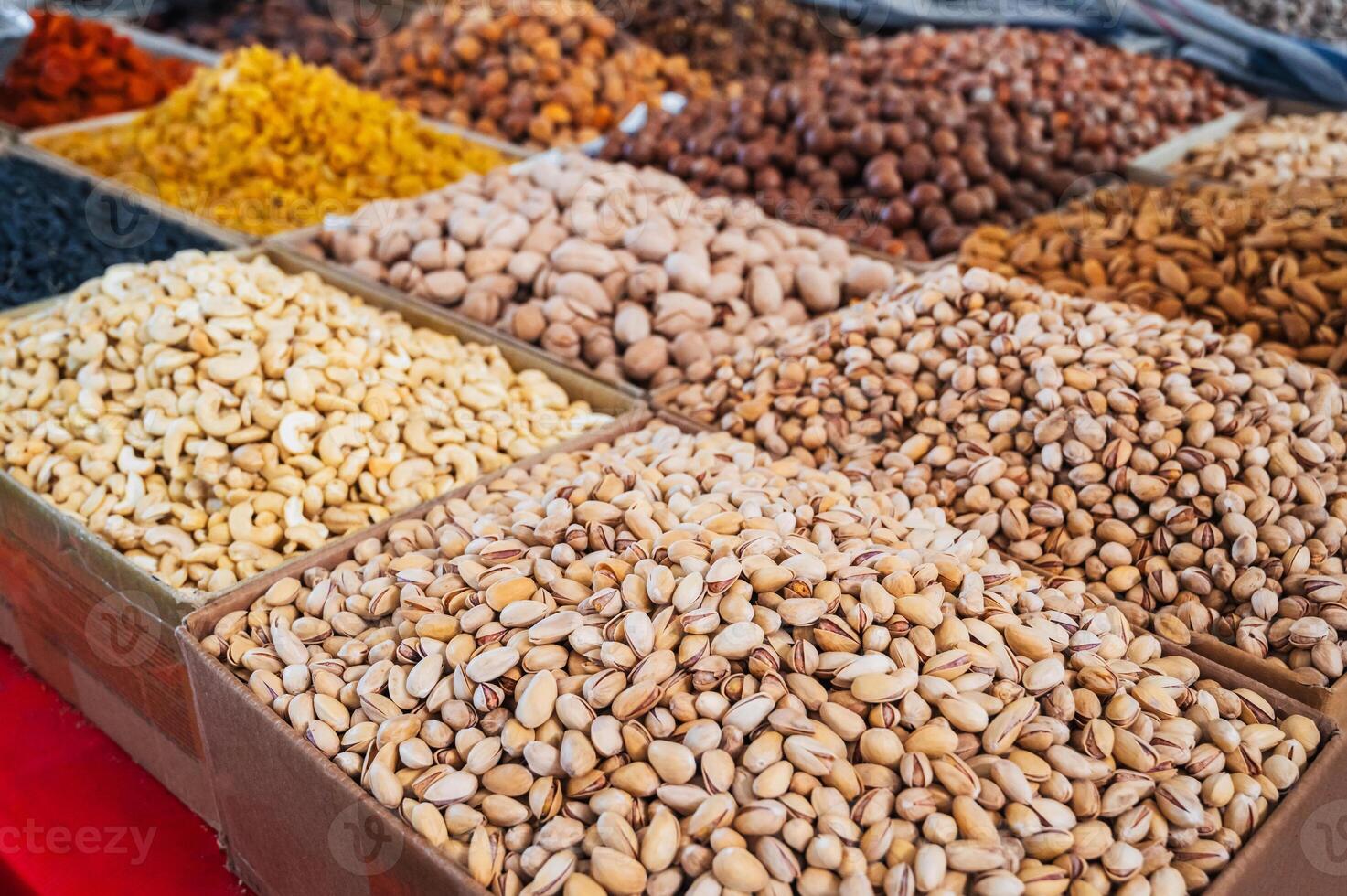 assortment of different variety nuts, dried fruits on counter at oriental Uzbek food bazaar. Almonds, raisins, pistachios, hazelnuts and cashews in market stall photo