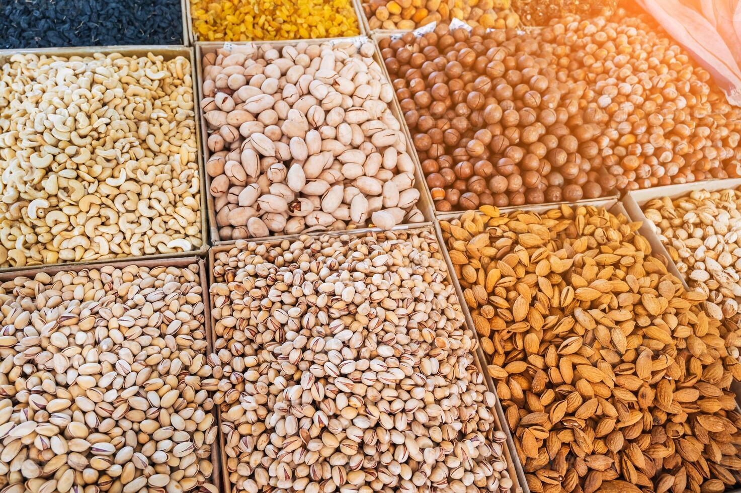 assortment of different variety nuts and dried fruits on counter at oriental bazaar. Almonds, raisins, pistachios, hazelnuts, macadamia in market stall photo
