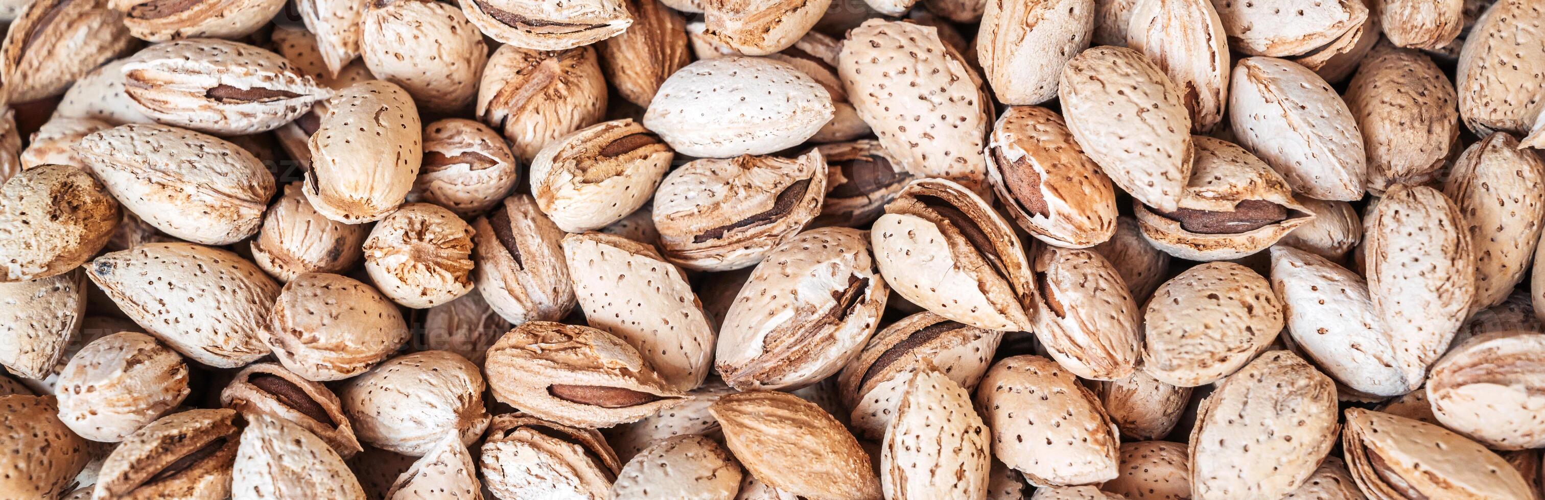 background with unpeeled almond kernels in textured shell on a store counter close-up photo