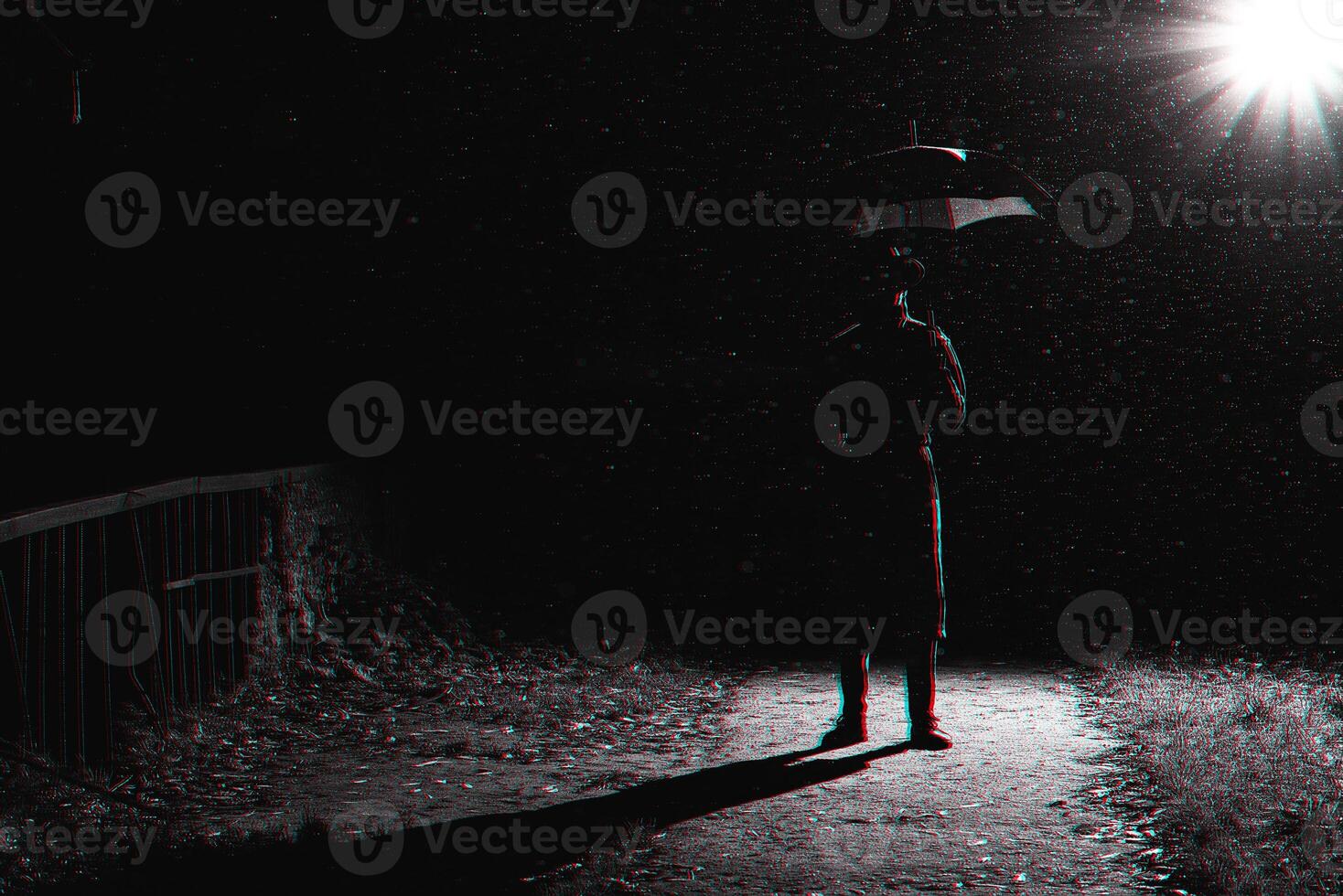 dark silhouette of a man in a raincoat and hat under an umbrella on the street in the rain photo
