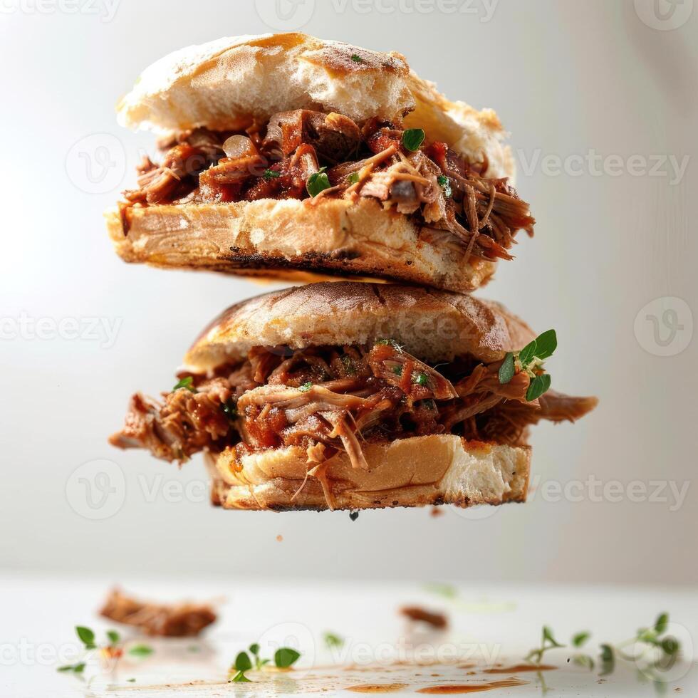 A close up of a pork belly sandwich with bacon, barbecue sauce and garnishes on top. photo
