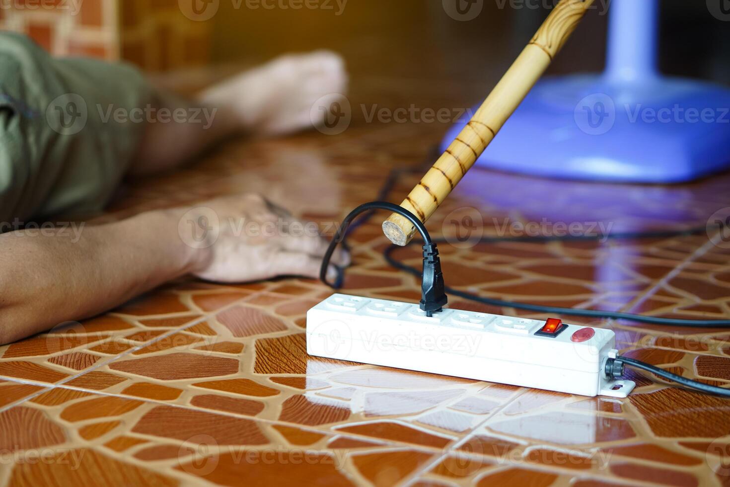 Using wooden stick is moving away the electric plug socket from the unconscious man who lay down on the floor. Concept, Electric Shock. Emergency basic rescue. First Aid photo