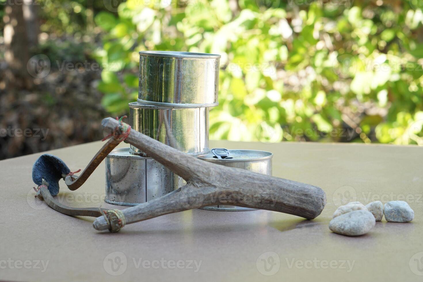 Slingshot, old cans and small rock bullets. Equipments for can shooting game. Concept ,Traditional game, Challenge, aim a catapult with stone bullet to cans and shoot. photo