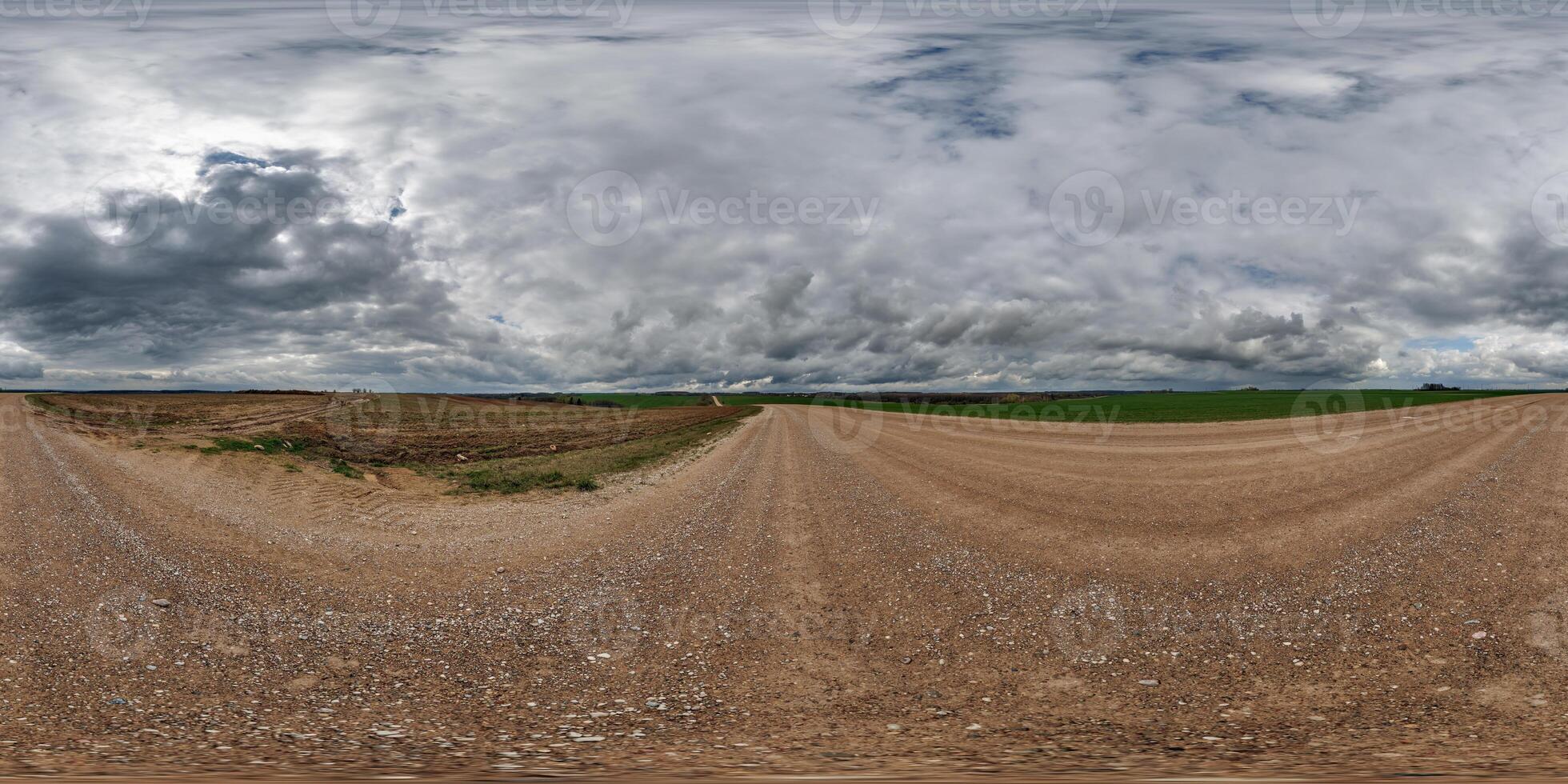 hdri 360 panorama on wet gravel road among fields in spring nasty day with storm clouds in equirectangular full seamless spherical projection, for VR AR virtual reality content photo