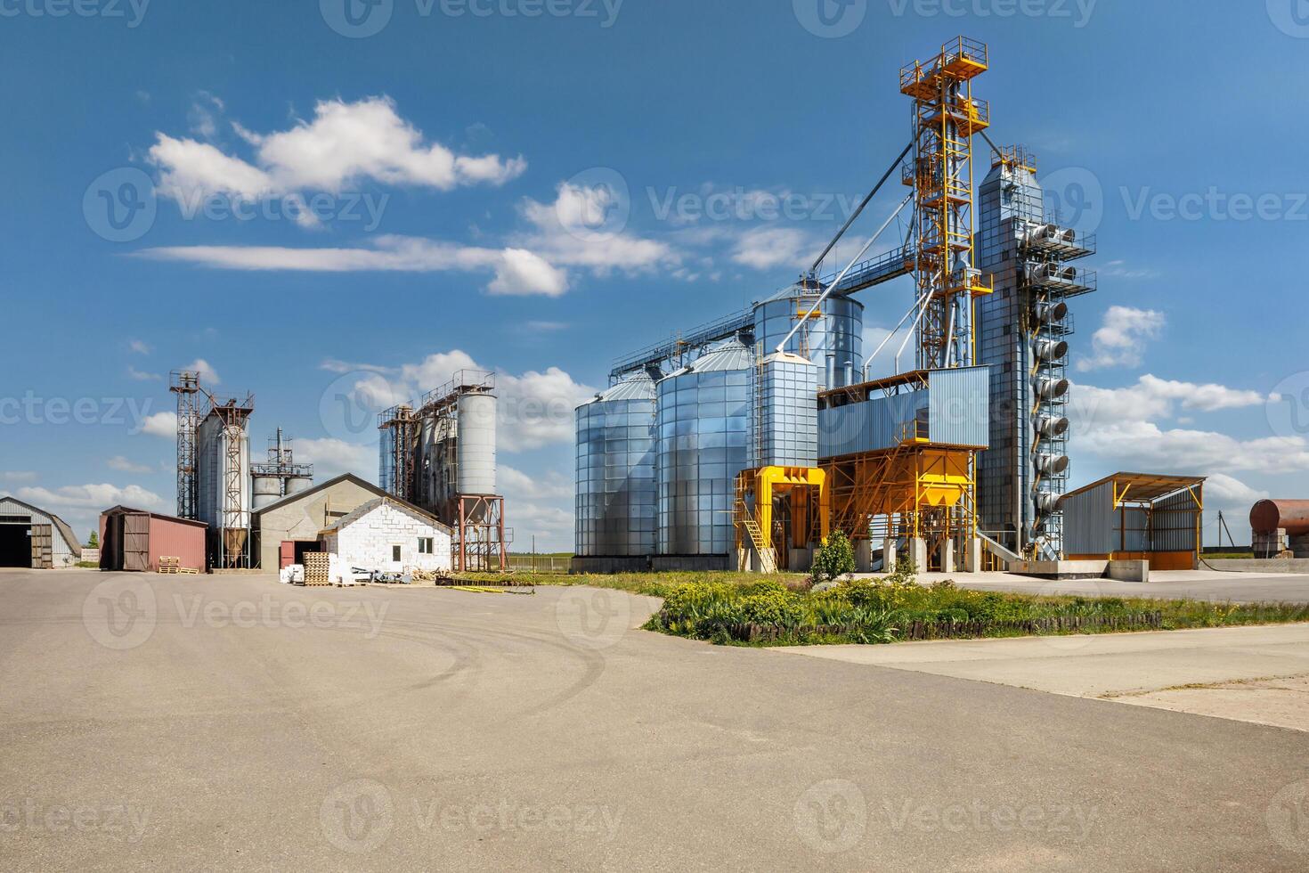 modern granary elevator with silver silos on agro-processing and manufacturing plant for processing drying cleaning and storage of agricultural products, flour, cereals and grain. photo