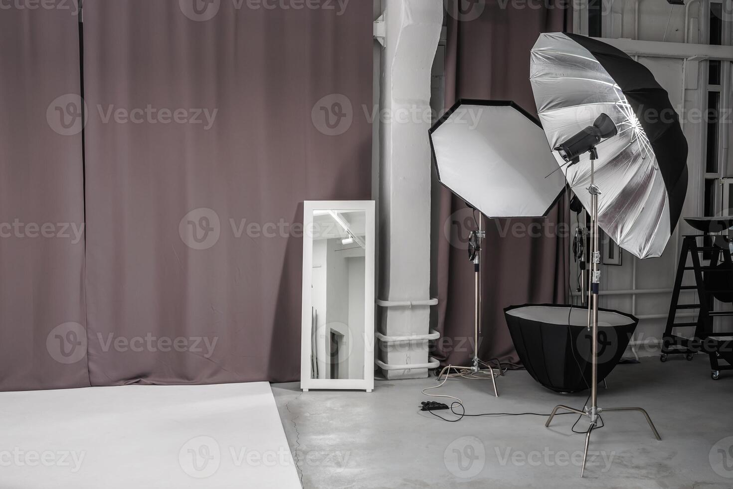 interior of bright space of photo studio with large white cyclorama with lighting equipment