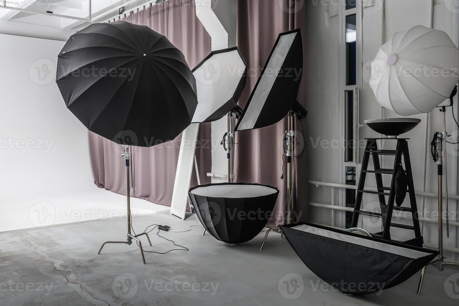 interior of bright space of photo studio with large white cyclorama with lighting equipment