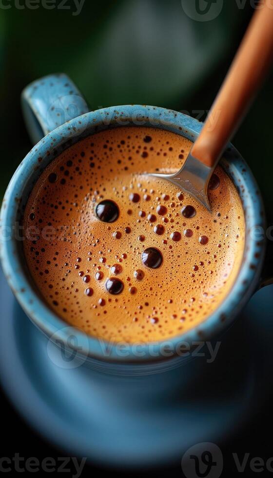 A steaming cup of coffee with a silver spoon resting inside it photo