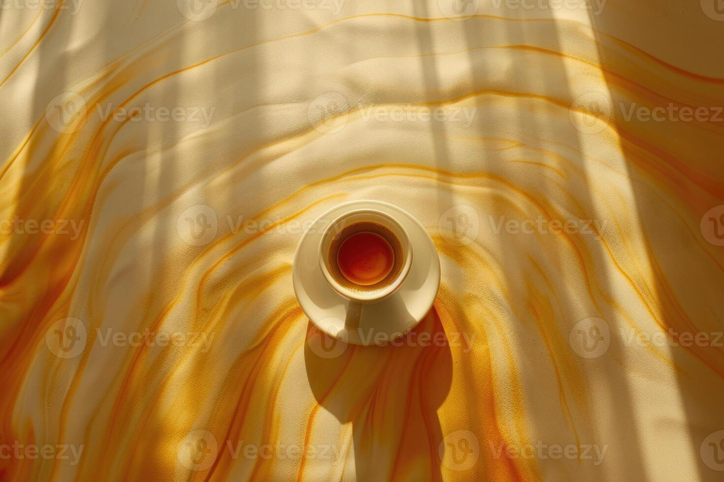 A steaming cup of coffee resting on a saucer atop a yellow table cloth photo