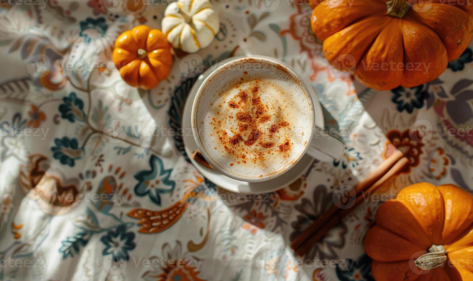 A pumpkin spice latte with a cinnamon stick and small pumpkins photo