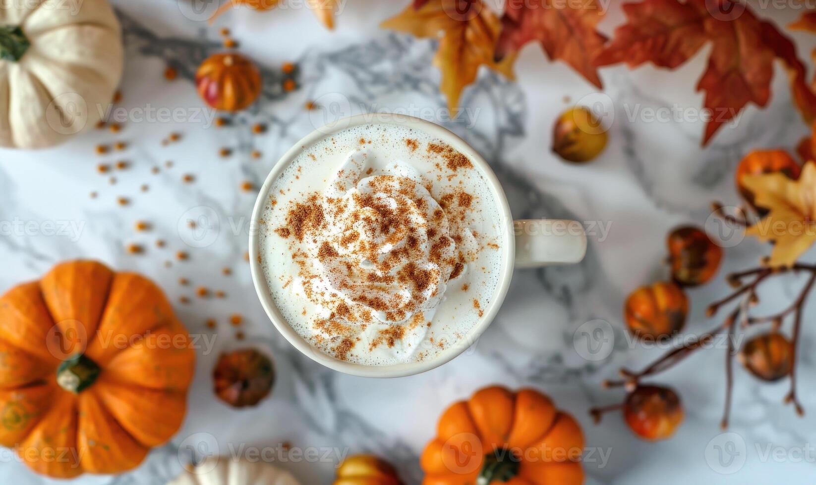 A pumpkin chai tea latte with cinnamon, surrounded by small pumpkins and autumn leaves photo